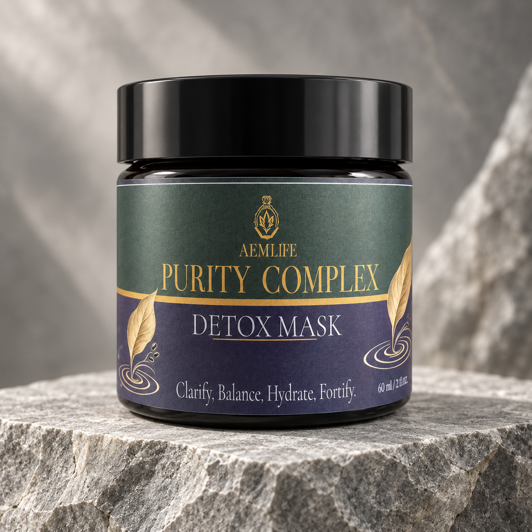 A jar of AEMLife Purity Complex Detox Mask sits on a textured gray stone slab with a blurred gray stone background. The product container has a black lid and a label that is dark green on top and deep purple on the bottom, with gold lettering and decorative leaf graphics.