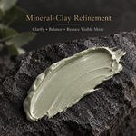 A thick, textured smear of mineral-clay skincare cream in a muted sage green color, presented on a dark textured rock with elegant text overlay at the top reading 'Mineral-Clay Refinement'.